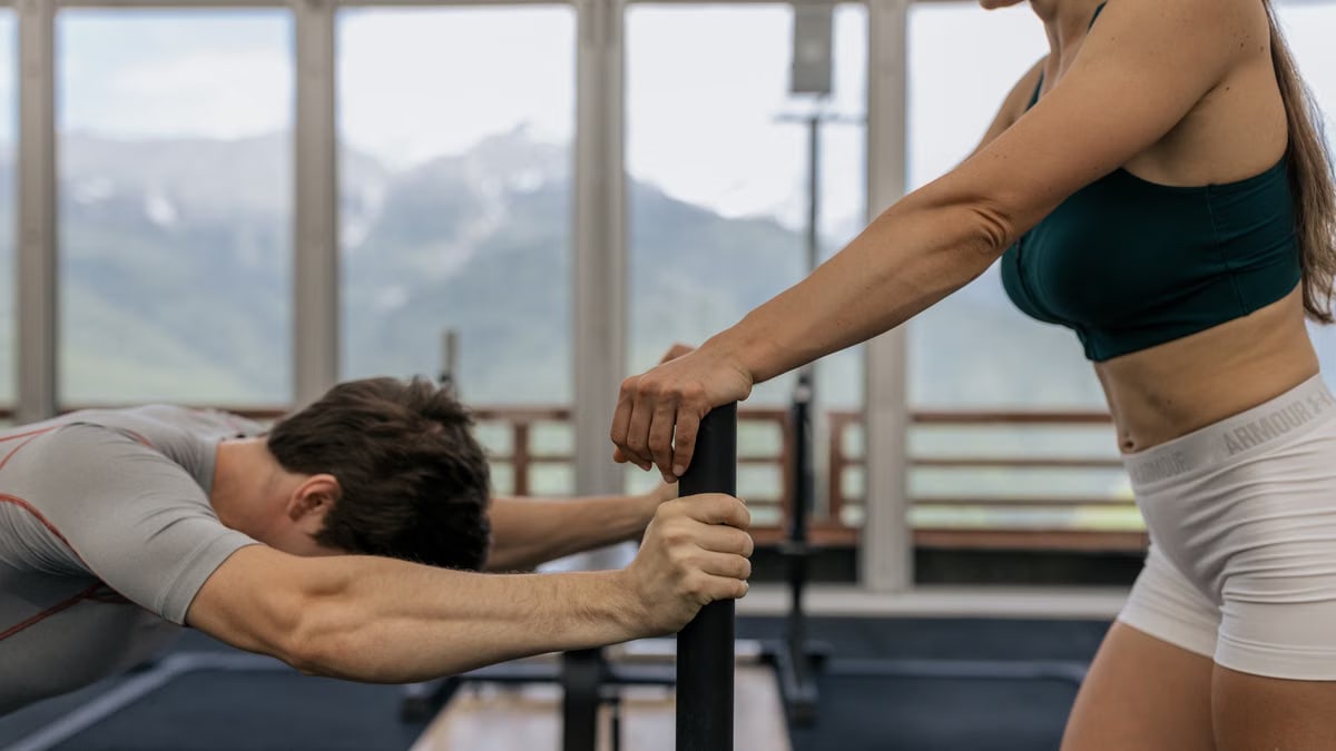 A couple working out together at an indoor gym with mountain views.